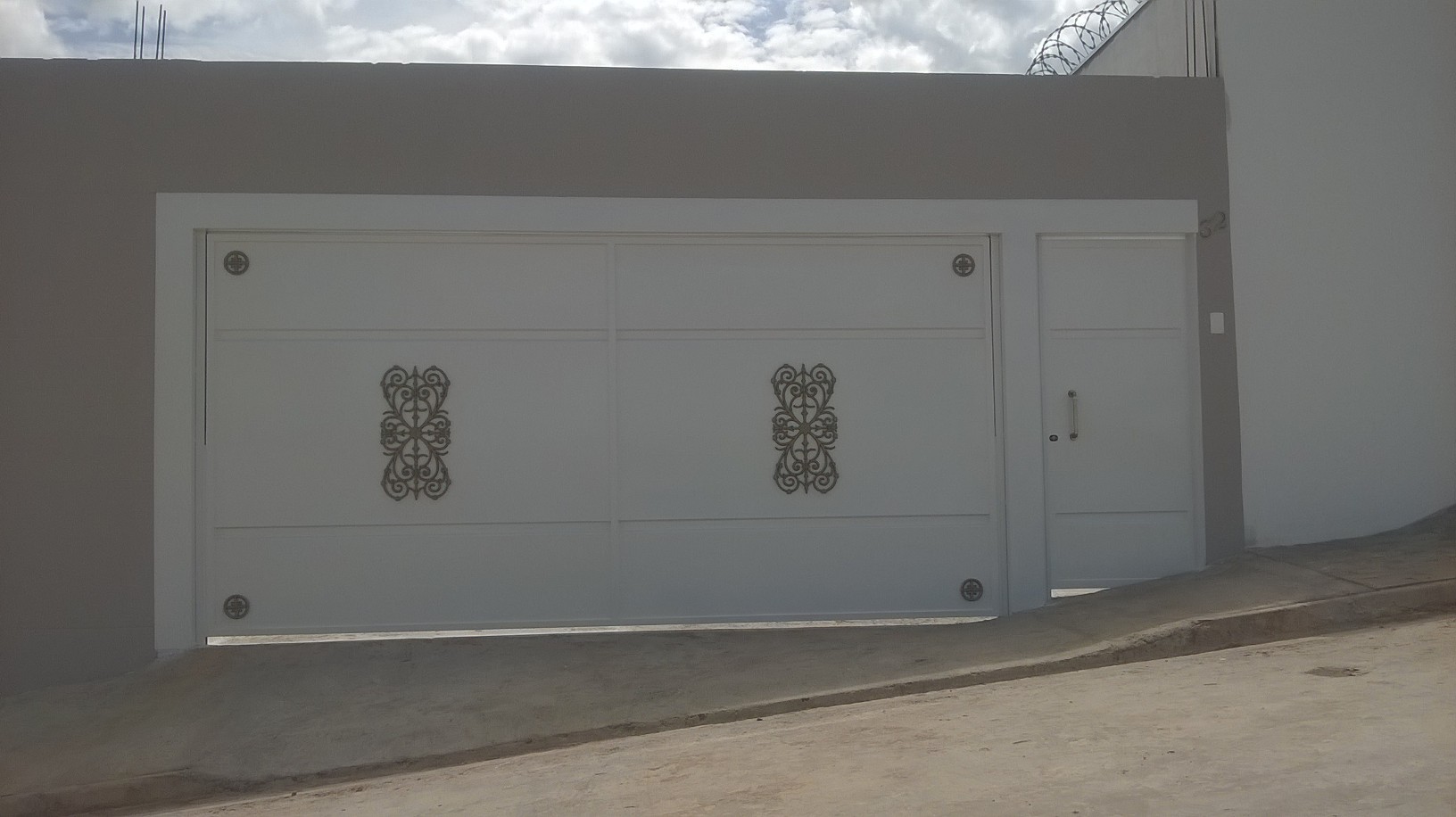 Portão basculante branco com detalhes ornamentais em ferro, instalado pela Serralheria Amaral em Passos-MG