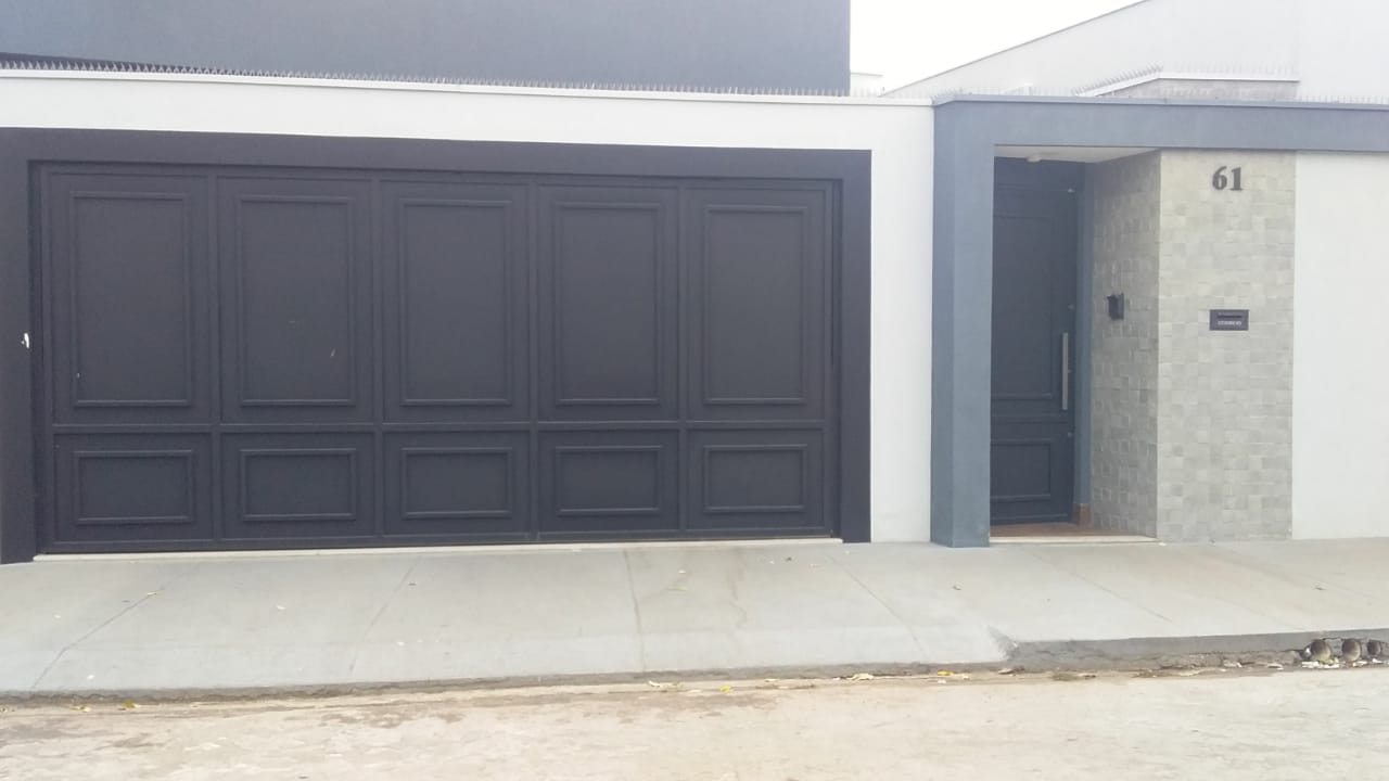 Fachada residencial contemporânea com portão e porta em tom escuro, projeto executado em parceria com profissionais da área
